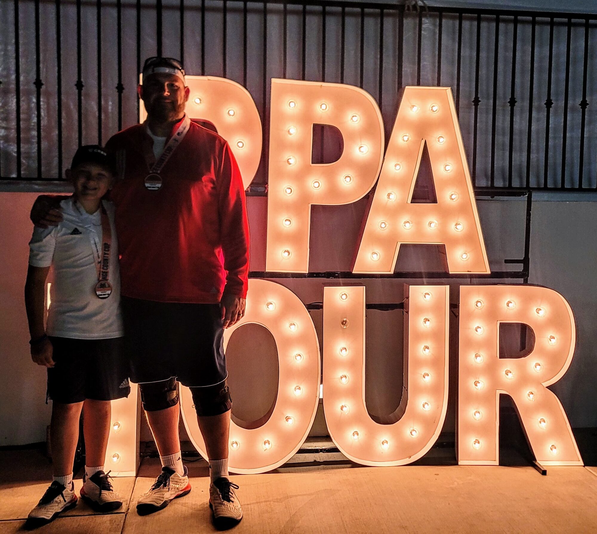 Jett and Dad in front of the PPA Tour sign in San Clemente